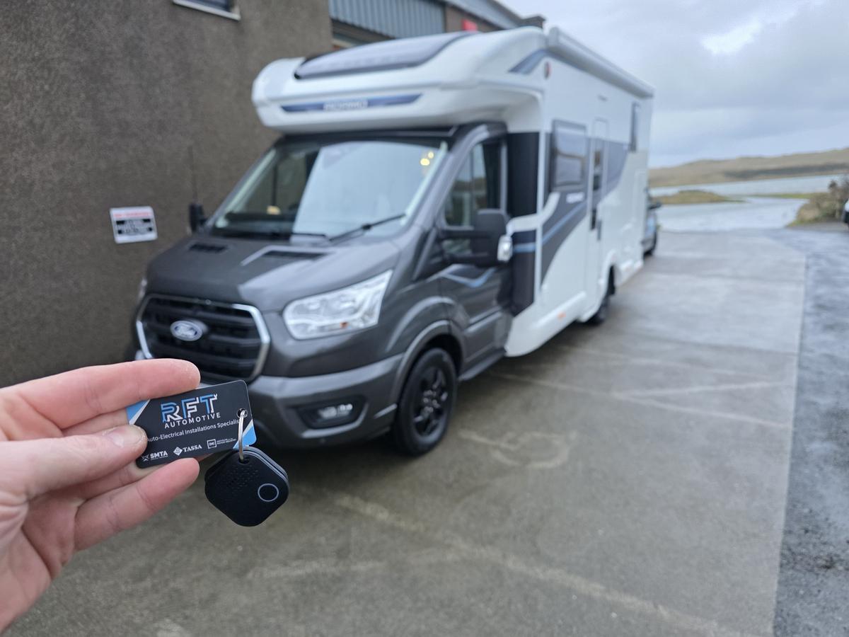 RFT Automotive tracker tag held up in front of a Ford-based motorhome
